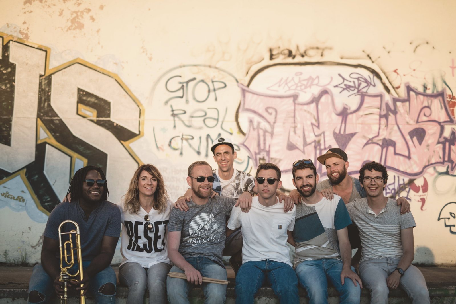 Les membres d'Antydot réunis devant un mur de graffitis